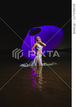 Young slim girl posing in water with abstract purple light effect 117248816
