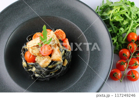 Black spaghetti. Black seafood pasta in white plate on black background with copy space. 117249246