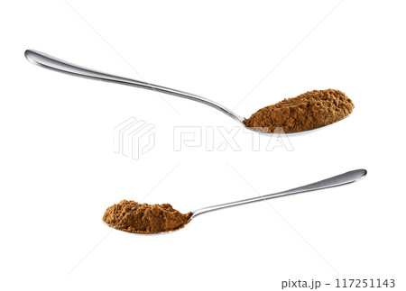 large and small steel spoons filled with cinnamon powder isolated on a white background. Side view. 117251143