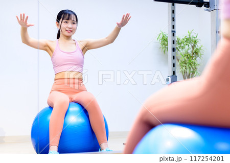 スポーツジムでバランスボールに乗る若い女性 ダイエット パーソナルジム 筋トレ女子 トリミングアップ スポーツジムでバランスボールに乗る若い女性 ダイエット パーソナルジム 筋トレ女子 トリミングアップ 117254201