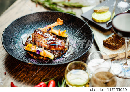 Corn chicken supreme. Beluga lentils, Old Ammerlander cheese, mini zucchini, red wine sauce. Delicious healthy traditional food closeup served for lunch in modern gourmet cuisine restaurant 117255030