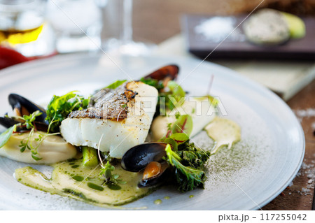 Cod fillet with cauliflower cream, asparagus, clam-wine sauce and mussles. Delicious seafood fish closeup served on a table for lunch in modern cuisine gourmet restaurant 117255042