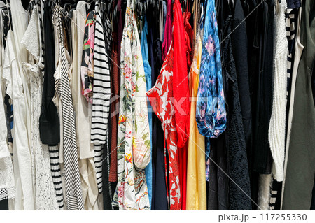 A colorful assortment of various clothing items hanging on a rack in a store 117255330
