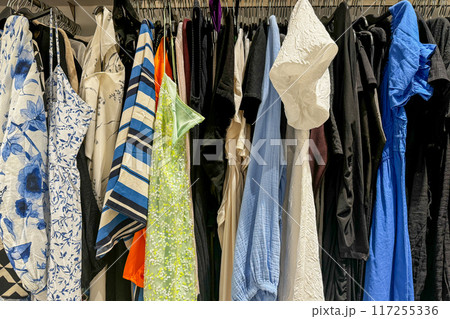 A closet filled with a variety of colorful and patterned clothing items hanging on hangers A closet filled with a variety of colorful and patterned clothing items hanging on hangers 117255336
