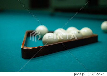 A man's hands stack billiard balls into a pyramid on a billiard table. A man collects balls into a billiard triangle to start a new game of billiards. A man's hands stack billiard balls into a pyramid on a billiard table. A man collects balls into a billiard triangle to start a new game of billiards. 117255573