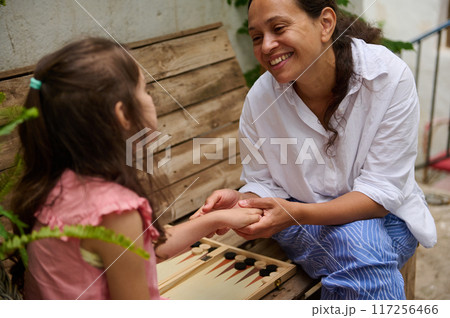 A mother and daughter spend quality time baking croissants together in a cozy kitchen. The little girl thoughtfully arranges baked goods while learning the art of cooking. A mother and daughter spend quality time baking croissants together in a cozy kitchen. The little girl thoughtfully arranges baked goods while learning the art of cooking. 117256466