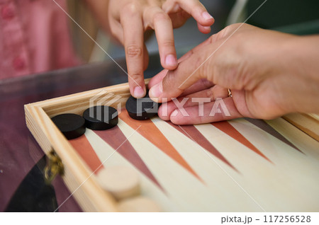 Close-up of a parent and child playing a game of backgammon together Close-up of a parent and child playing a game of backgammon together 117256528