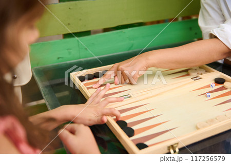 Close-up of hands playing backgammon on a wooden board game setup Close-up of hands playing backgammon on a wooden board game setup 117256579