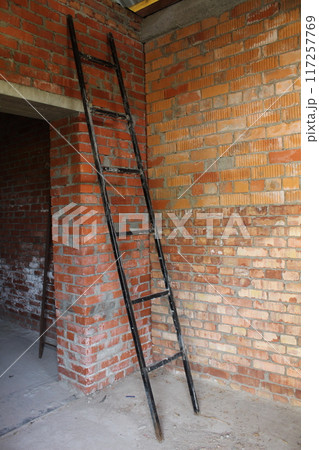 A black staircase leans against a brick wall. Construction Equipment A black staircase leans against a brick wall. Construction Equipment 117257769