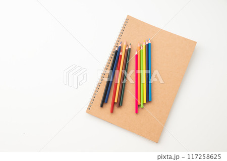 Colored pencils with notebook on white background. 117258625