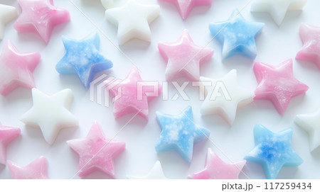 Colorful star-shaped candies in blue and pink on white surface for party decorations. Colorful star-shaped candies in blue and pink on white surface for party decorations. 117259434
