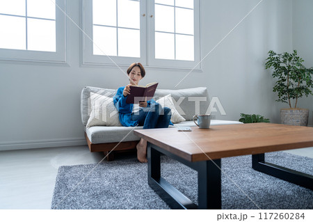 ソファーで本を読むミドルの女性 117260284