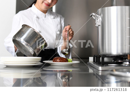 料理を皿に盛る若いアジア人の女性調理師 料理を皿に盛る若いアジア人の女性調理師 117261318