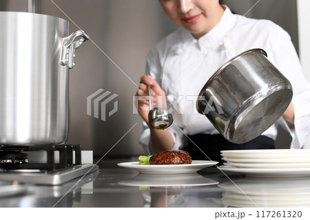 料理を皿に盛る若いアジア人の女性調理師 料理を皿に盛る若いアジア人の女性調理師 117261320