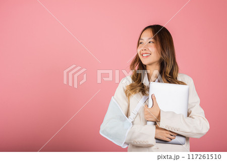 Asian business woman confident smiling broken arm after accident and wear arm splint for treatment but still have to work she hold laptop computer studio isolated on pink background,copy space Asian business woman confident smiling broken arm after accident and wear arm splint for treatment but still have to work she hold laptop computer studio isolated on pink background,copy space 117261510