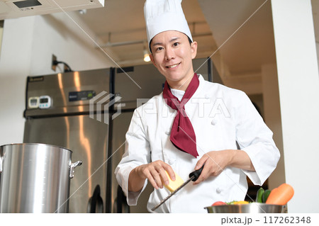 厨房でグレーターでチーズを削る男性調理師 117262348