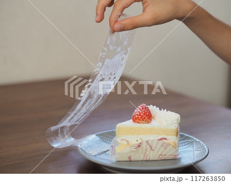 ケーキのフィルムをはがす子供の手 117263850
