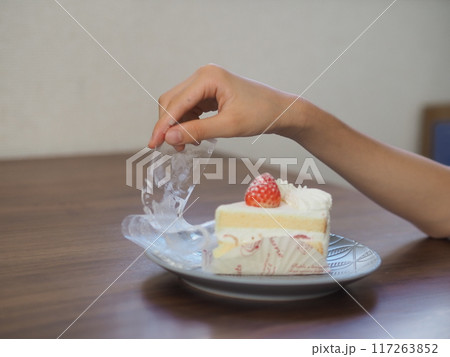 ケーキのフィルムをはがす子供の手 117263852