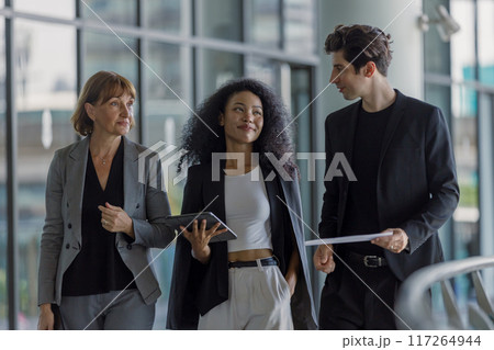 Diverse group businesspeople walking to meeting at modern office. 117264944