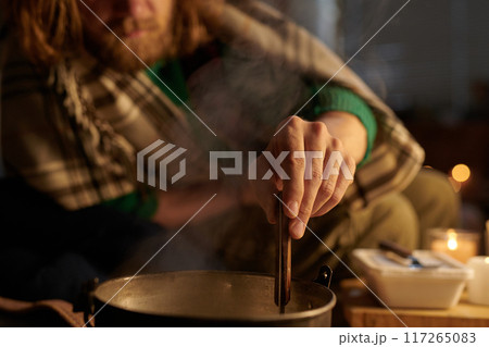 Stirring Soup in Pot on Cold Winter Evening by Candlelight 117265083
