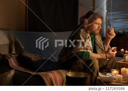 Relaxing Man in Cozy Indoor Setting Holding Cigarette Relaxing Man in Cozy Indoor Setting Holding Cigarette 117265086