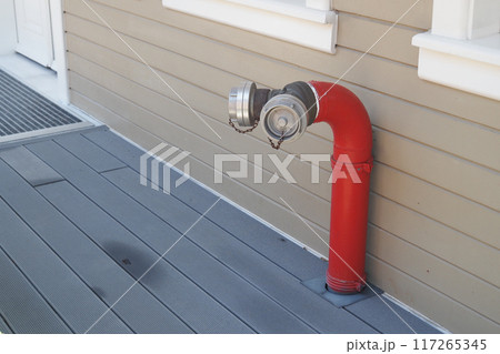 A Bright Red Fire Hydrant Attachment Installed on a Wooden Deck in an Urban Area 117265345
