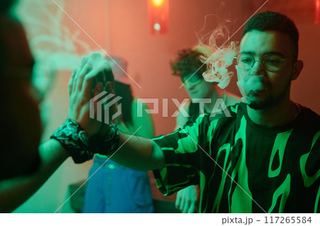 Young man exhaling smoke from mouth 117265584