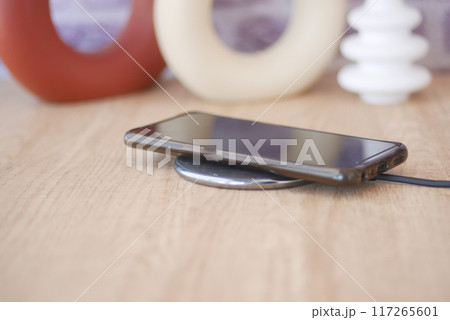 charging Smartphone using Wireless Charging Pad, top view  117265601