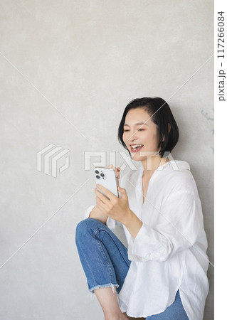 部屋でスマホを操作する戻る女性 117266084