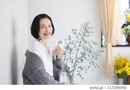 部屋でスマホを操作する戻る女性 117266092