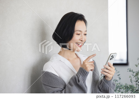 部屋でスマホを操作する戻る女性 117266093