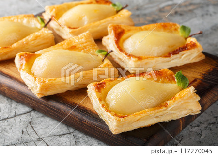 Caramelized pears baked in puff pastry and stuffed with nuts and cream cheese close-up. Horizontal 117270045