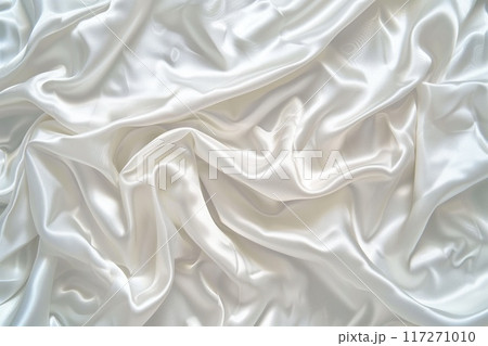 Close-up view of white fabric with slight curl edges, wrinkled texture. Fabric possibly clothing or decorative item. Blurred background focuses on fabric textured appearance. 117271010