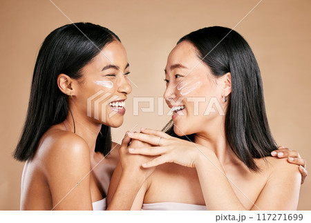 Laughing, beauty and excited women with cream for face isolated on beige studio background. Wellness, smile and Asian model friends with sunscreen for love of cosmetics and dermatology on a backdrop 117271699
