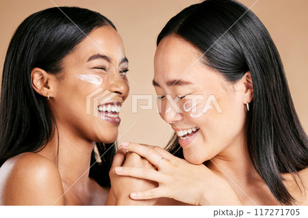 Happy, beauty and skincare women with cream for face isolated on a beige studio background. Wellness, smile and Asian model friends with sunscreen for love of cosmetics and dermatology on a backdrop Happy, beauty and skincare women with cream for face isolated on a beige studio background. Wellness, smile and Asian model friends with sunscreen for love of cosmetics and dermatology on a backdrop 117271705