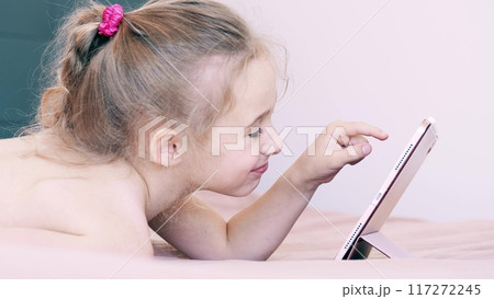 Little girl uses her pink tablet computer at home Little girl uses her pink tablet computer at home 117272245