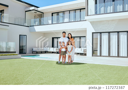 Family, children and real estate with a girl, parents and sister in the backyard of their home together. House, garden and property with a man, woman and kids standing on grass during the day Family, children and real estate with a girl, parents and sister in the backyard of their home together. House, garden and property with a man, woman and kids standing on grass during the day 117272387