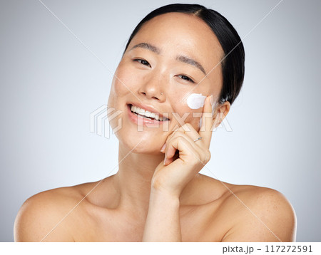Face, skincare and beauty with a model asian woman applying lotion or moisturizer to her skin in studio. Cosmetics, antiaging and wellness with a young female inside to promote a skin product Face, skincare and beauty with a model asian woman applying lotion or moisturizer to her skin in studio. Cosmetics, antiaging and wellness with a young female inside to promote a skin product 117272591