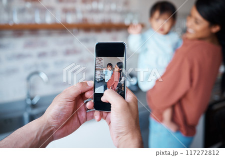 Father taking a picture of mother and baby on a phone in the kitchen of their family house. Love, care and man taking photo on smartphone of a happy and proud mom bonding with her child in their home 117272812