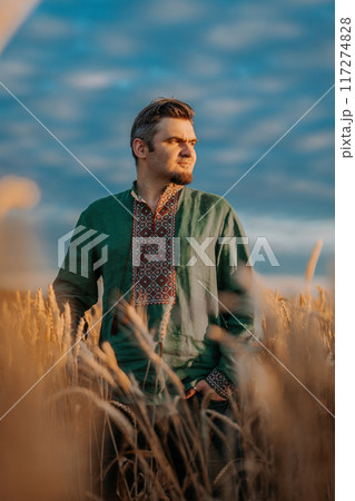 Ukrainian man in vyshyvanka shirt, traditional ornament standing in wheat field Ukrainian man in vyshyvanka shirt, traditional ornament standing in wheat field 117274828