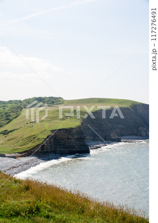 砂利が続く海岸線と海水の浸食で断崖絶壁になった入江　南ウェールズの郊外にて 117276491