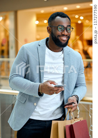 handsome young bearded man holding smartphone, credit card 117277590