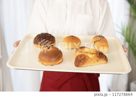 ベーカリーの女性スタッフが持つ焼きたてのパン ベーカリーの女性スタッフが持つ焼きたてのパン 117278664