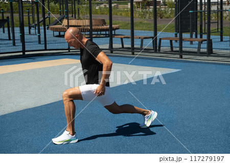 Athlete handsome man make fitness exercises and stretch on sports public park. Workout routine. Warm-up exercises. 117279197