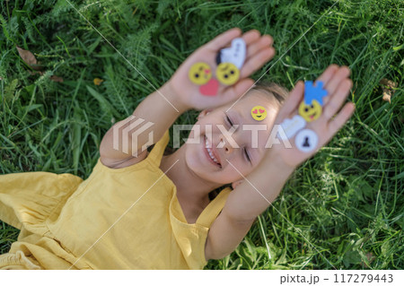 The girl is lying on the grass of the lawn with a variety of small emoticons, icons and social media widgets in hands 117279443