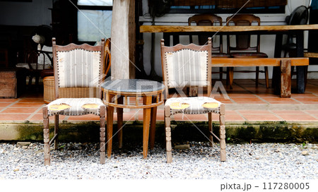 Two old, wooden chairs placed in front of a cozy coffee shop, Two old, wooden chairs placed in front of a cozy coffee shop, 117280005