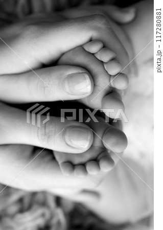 Mother is doing massage on her baby foot. Closeup baby feet in mother hands. Prevention of flat feet, development, muscle tone, dysplasia. Family, love, care, and health concepts. Black and white. 117280881
