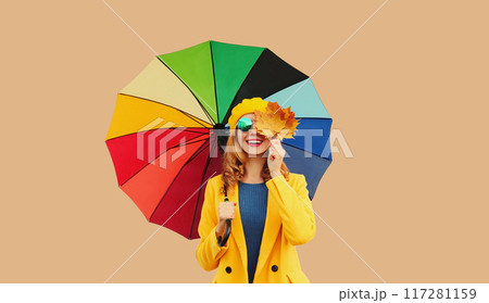Autumn outfit, beautiful smiling young woman holds yellow maple leaves with colorful umbrella 117281159
