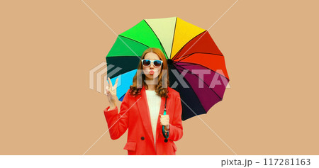Autumn color style outfit, stylish young woman posing with colorful umbrella blowing a kiss 117281163