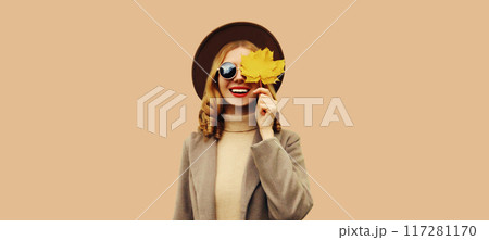 Autumn color style outfit, portrait of beautiful smiling young woman with yellow maple leaves 117281170